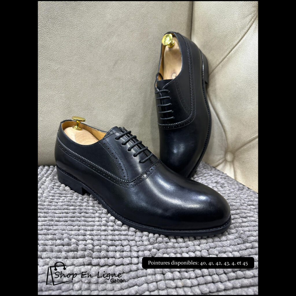 Chaussures de ville Oxford homme en cuir noir brillant avec détails perforés, disposées sur un tapis gris.