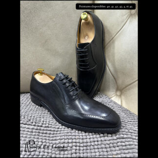 Chaussures Richelieu de luxe pour homme en cuir noir poli avec détails perforés sur les quartiers, montrées sur embauchoirs.