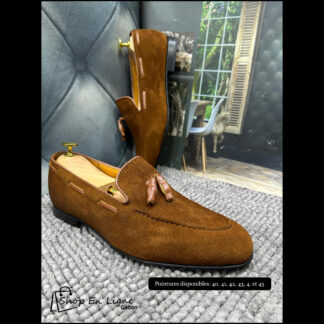 Mocassins homme en daim marron avec pompons en cuir, présentés sur embauchoir en bois doré, vue de côté et de face, semelle noire, style loafer chic et confortable – Shop En Ligne Gabon